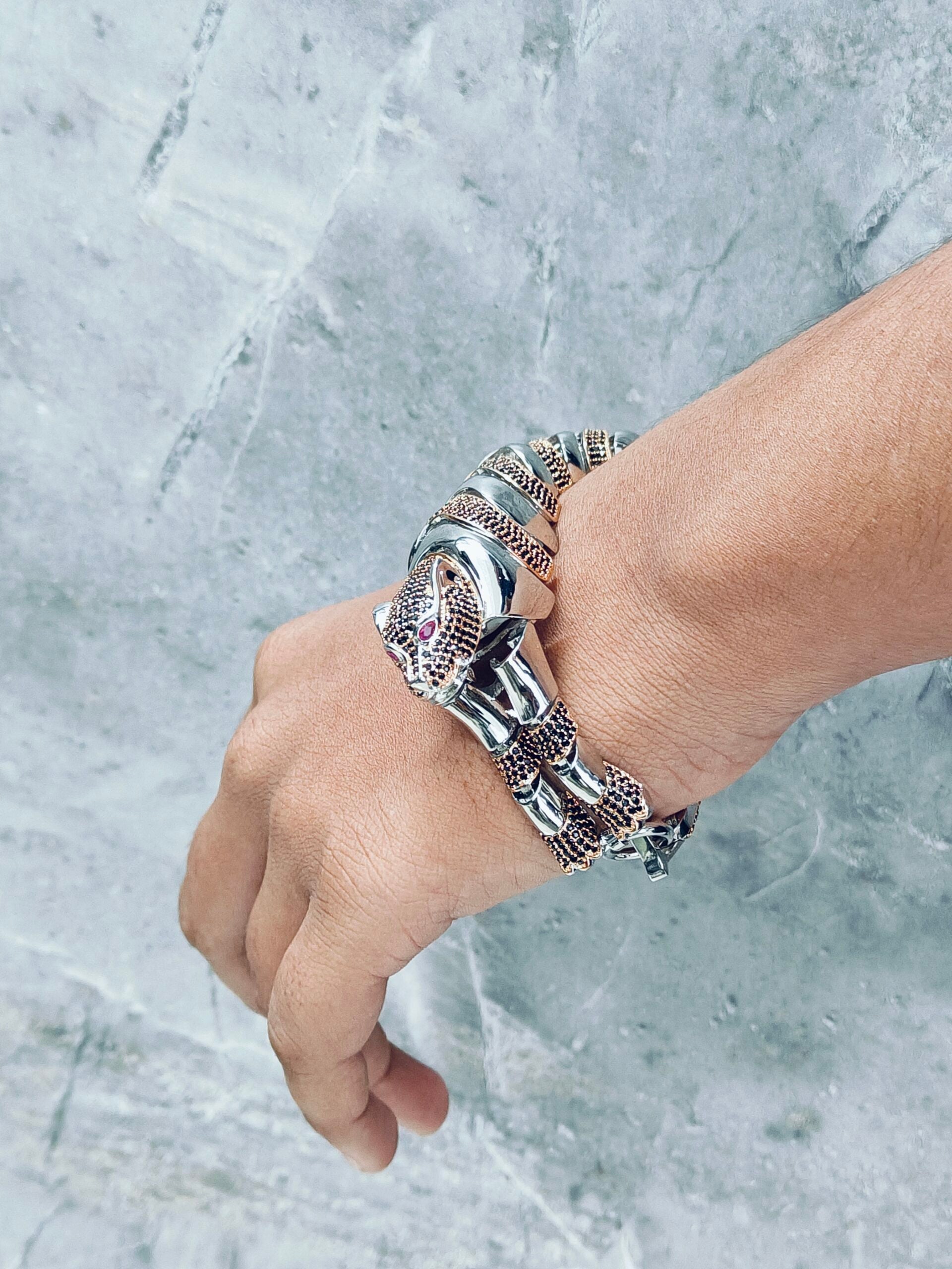 Hand wearing multiple silver bracelets on a marble background